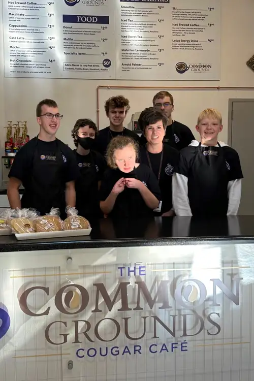 Kids standing behind a food counter for the couger cafe.