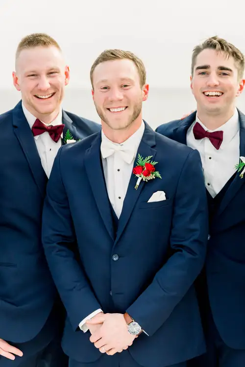 Groom and groomsmen in black tuxedos with hands folded