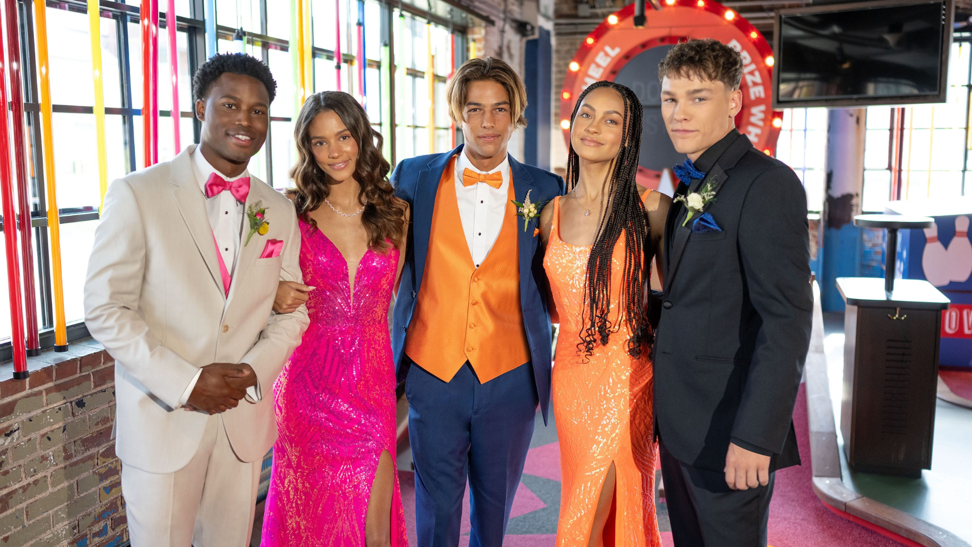 A group of teens with vibrant tuxedos and dresses in prom
